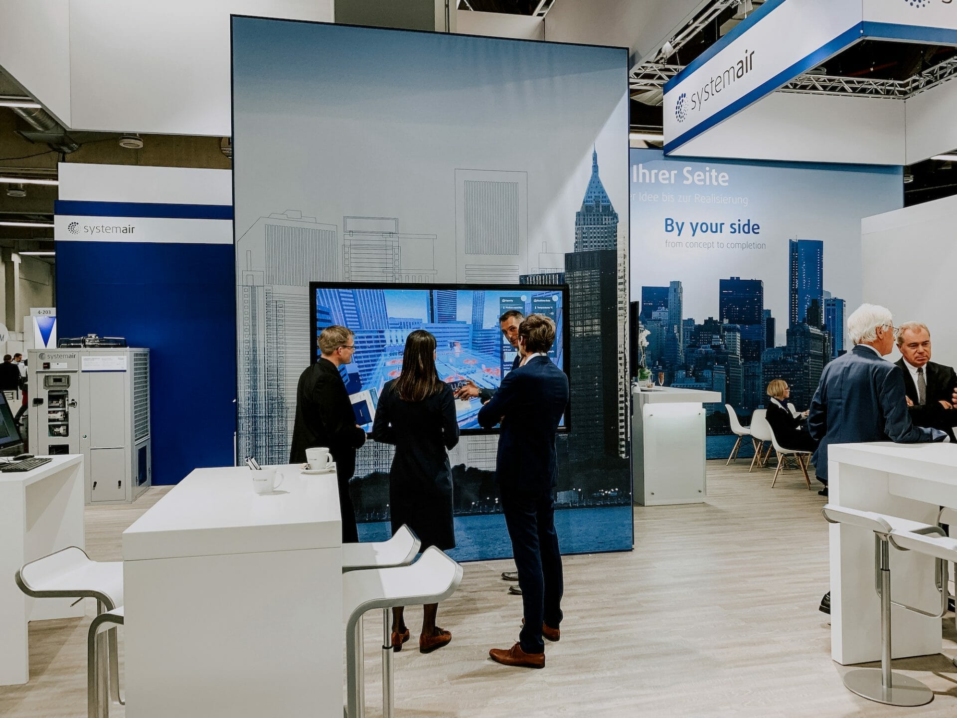 Wide shot of a systemair exhibition stand with visitors and employees interacting throughout